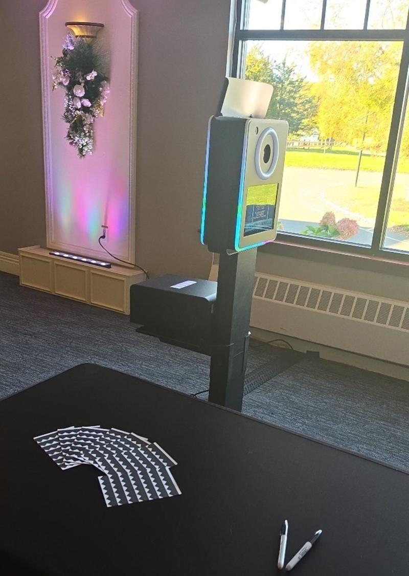 The Golden Hour Booth NY photo booth set up at an event venue, with print strips and markers on the table